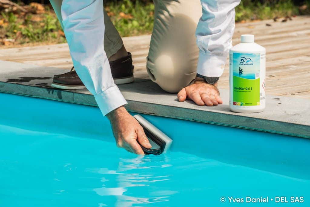 Personne qui nettoie le liner de sa piscine avec une éponge et des produits de la marque Chemoform. L'image a un but informatif.